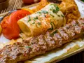 Kebab na talerzu z warzywami i plackiem.