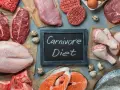 Różnorodne mięsa, ryby i jaja na stole. Tabliczka z napisem "Carnivore Diet" sugeruje potencjalne dieta karniwora efekty.