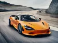 Pomarańczowy McLaren 750S z czarnym dachem sunie po torze wyścigowym, tworząc dynamiczny obraz prędkości i mocy.