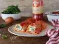 Cannelloni ricotta e spinaci fumanti, conditi con passata Mutti e formaggio filante, pronti per essere gustati.