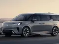 Szary luksusowy van elektryczny Volvo EM90 w ruchu drogowym nad morzem.