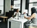 Dos mujeres discuten sobre el impuesto de sociedades y contabilidad en una oficina moderna.