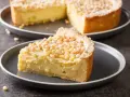 Una fetta di torta con crema pasticcera e pinoli, cosparsa di zucchero a velo. Un dolce invitante.