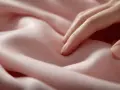 Dedos acarician un suave tejido cupro que se arruga delicadamente, creando un juego de luces y sombras.