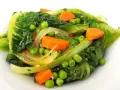 Un assortiment coloré de légumes verts feuillus, de pois et de carottes en dés, rappelant une jardinière de légumes fraîchement préparée.