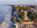 Widok z lotu ptaka na latarnię morską w Darłowie, plażę i nadmorskie miasteczko.