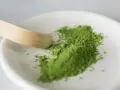 Zielony proszek matcha na białej miseczce, gotowy do przygotowania napoju. Poznaj, jak smakuje matcha – intensywnie, lekko gorzko, z nutą słodyczy.
