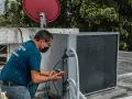 Technik sprawdza czujnik ciśnienia klimatyzacji, podłączając manometr do jednostki zewnętrznej.