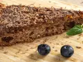 Wilgotne ciasto z płatków owsianych z polewą czekoladową i wiórkami, ozdobione borówkami i miętą.