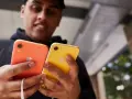 Mężczyzna trzyma dwa telefony: pomarańczowy i **iphone xr żółty**.