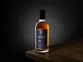 Packshot photo d'une bouteille de Calvados SASSY XO ambré, posée sur une table en bois.