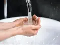 Dłonie łapią strumień wody z kranu. Zastanawiasz się, ile kosztuje kubik wody?