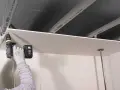 Persona con guanti avvita una lastra di cartongesso al soffitto metallico, un progetto di cartongesso fai da te.