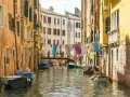 Angoli nascosti di Venezia: un canale tranquillo con barche ormeggiate e panni stesi ad asciugare tra case colorate.