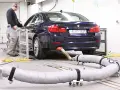 Blauer BMW auf einem Prüfstand für Abgastests. Ein Techniker überwacht die Messungen, die für die Euro 6-Abgasnorm relevant sind.
