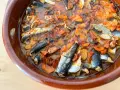 Sardinas en escabeche cocinándose en una cazuela de barro con verduras.