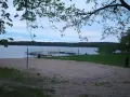 Plaża z boiskiem do siatkówki plażowej nad jeziorem w Borneńskim Sulimowie. W tle pomosty, żaglówki i las.