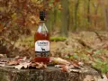 Glen Orchy Whisky steht auf einem Baumstumpf im Herbstwald, umgeben von Laub.