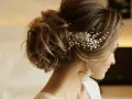 Eleganckie fryzury na komunie dla dorosłych: upięcie z perłową ozdobą i zwiewnymi lokami.