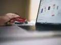 Dłoń trzyma kartę lojalnościową, przygotowując się do zakupów online. Może to być import z Wielkiej Brytanii, np. z sieci sklepów.