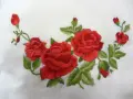Ricamo di rose rosse su tessuto bianco, un delicato punto pittura che evoca un giardino fiorito.