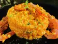 Arroz con gambones, un plato vibrante y delicioso, coronado con gambones jugosos y perejil fresco.