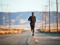 Un uomo corre su una strada deserta, circondato da tralicci dell'alta tensione. La corsa come fuga dalla depressione.