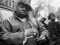 The notorious B.I.G. jak zginął. Raper w skórzanej kurtce i czapce, z towarzyszami, przed samochodem.