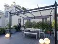 Terrazze arredate con tavolo, panche, sedie e scultura di gorilla sotto una pergola. Illuminazione soffusa con sfere luminose.