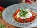 Ein Teller mit Ratatouille und Burrata, garniert mit frischen Kräutern. Dazu passt ein frischer Salat.