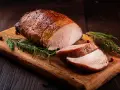 Saftiges Schweinefilet, perfekt gebraten, liegt auf einem Holzbrett mit Rosmarin und Beeren. Inspiration für Ihre nächsten Schweinefilet Rezepte.
