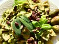 Farfalle condite con un saporito pesto di salvia, guarnite con pistacchi, basilico e olive.