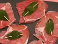 Fette di vitello pronte per la saltimbocca alla romana ricetta originale, con prosciutto crudo e foglie di salvia fissate con stuzzicadenti.