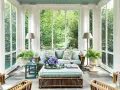 A serene screen porch with rattan furniture, plush cushions, and lush greenery. The natural screen porch materials create a cozy, inviting atmosphere.