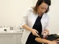 Lekarka w białym fartuchu bada skórę pacjenta za pomocą urządzenia.