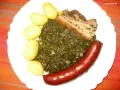 Gedünsteter Grünkohl mit Salzkartoffeln, Kassler und einer herzhaften Lungenwurst, die zum Kochen oder Braten bereit ist.