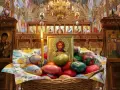A basket of colorful Easter eggs sits before an icon of Jesus in a richly decorated church, hinting at when Easter is celebrated in Europe.