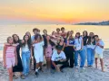 Groupe d'adolescents souriants sur une plage corse au coucher du soleil.