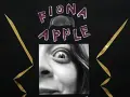 Fiona Apple, visage expressif, regard intense, entourée de lettres violettes et de pointes dorées.