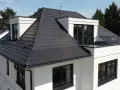 Modernes Haus mit dunkler Dachbeschichtung. Mögliche Nachteile der Dachbeschichtung: Hitzestau im Sommer, höhere Kosten bei Reparaturen.