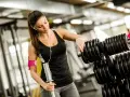 Kvinna väljer vikter på gymmet, bra gym tips för din träning.