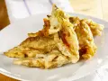 Fiori di zucca fritti dorati e croccanti su un piatto bianco, pronti per essere gustati.