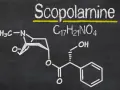 Struktura chemiczna skopolaminy, C₁₇H₂₁NO₄, narysowana kredą na tablicy.