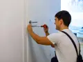 Hombre arregla manija de puerta con destornillador. Podría estar a punto de cambiar marco puerta.