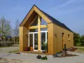 Nowoczesny domek na ogródek działkowy z drewnianą elewacją i dużymi oknami. Idealne miejsce na relaks wśród zieleni.