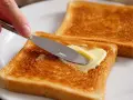 Goldbraunes Brot im Ofen getoastet, wird nun mit Butter bestrichen. Ein Genuss!