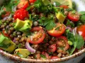 Fresca insalata di lenticchie estiva con pomodorini, avocado, cipolla rossa e prezzemolo.