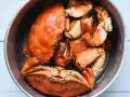 Un cuenco metálico lleno de buey de mar cocido, con sus caparazones anaranjados y pinzas visibles.