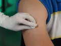 Ręka w rękawiczce dezynfekuje ramię przed podaniem zastrzyku. To przygotowanie do iniekcji śródskórnej.