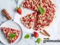 Pyszna tarta z truskawkami i kruszonką, udekorowana miętą, obok laski cynamonu i świeżych truskawek.